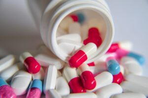 close up view of medications and pills laid across a flat surface pouring out a bottle